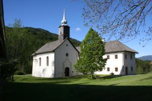 an old white church with a steeple on a green field at Klösterle Haus Egon in Arriach