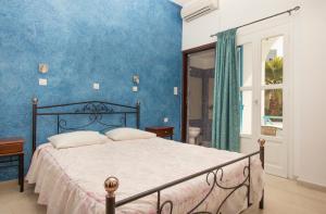 a bedroom with a bed and a blue wall at Villa Pelekanos in Karterados