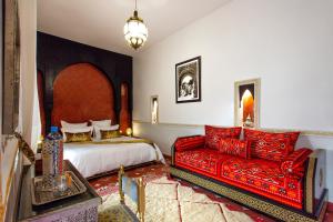 een slaapkamer met een bed en een rode bank bij Riad en exclusivité Maison d hôtes Chamade & Spa in Marrakesh