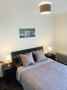 a bedroom with a bed with two lamps on tables at Superbe Appartement lumineux proche Disney in Montévrain +2 photos