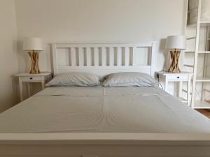 ein großes weißes Bett mit zwei Nachttischen und zwei Lampen in der Unterkunft B&B L'edera in Trient