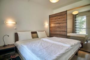 Schlafzimmer mit einem großen Bett mit einem Kopfteil aus Holz in der Unterkunft SunGarden Apartments - hostAID in Siófok