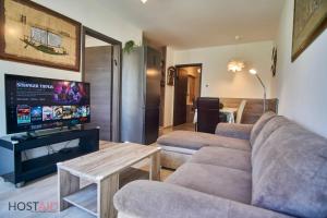 uma sala de estar com um sofá e uma televisão de ecrã plano em SunGarden Apartments - hostAID em Siófok