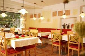 restauracja z białymi stołami, krzesłami i światłami w obiekcie Apart-Hotel Pension Roßmayer w mieście Bad Füssing