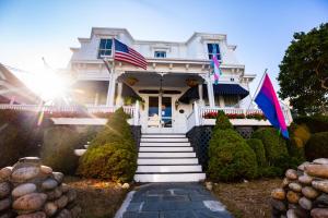 Uma casa branca com duas bandeiras americanas. em Brasswood Inn em Provincetown