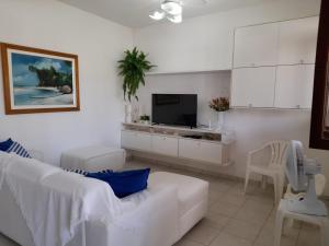 a white living room with a white couch and a tv at Casa de praia aconchegante em Sonho Verde in Paripueira