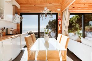 une salle à manger avec une table et des chaises blanches dans l'établissement Madeira Sunset Cottage - Nature Retreat, à Ponta do Pargo