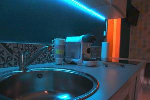um balcão de casa de banho com um lavatório e uma luz azul em Studio Nature, proche du centre-ville em Dijon