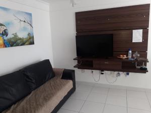 a living room with a couch and a flat screen tv at Edificio Castel Gandolfo in Guarapari