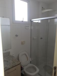 a bathroom with a toilet and a glass shower at Edificio Castel Gandolfo in Guarapari