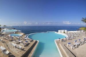 Las Lagunas的住宿－the million view room habitacion en resort solo adultos，一个带椅子的游泳池,背景是大海