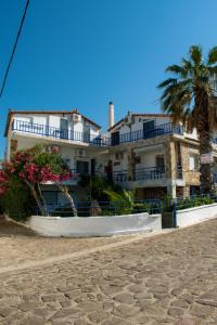 une grande maison blanche avec des palmiers devant elle dans l'établissement Efterpi Aggeli, à Loutrópolis Thermís