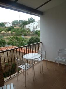 einen Balkon mit einem Tisch, 2 Stühlen und einem Fenster in der Unterkunft Alojamiento VuT Rupurupay A in Aldeadávila de la Ribera