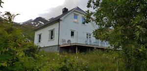 ein weißes Haus auf einem Hügel mit Bergen im Hintergrund in der Unterkunft Pilan Lodge Lofoten in Vestpollen