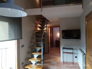 a spiral staircase in a living room with a tv at Apartament casa Rural Cal Xico d'Adrall -La Seu d'Urgell-Andorra in Adrall