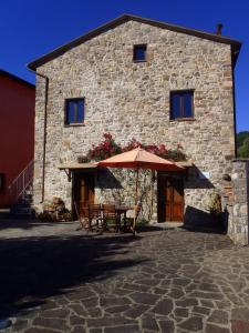 a building with a table and an umbrella in front of it at Agriturismo La Villa in Bolano