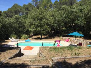 a swimming pool with umbrellas and chairs at Villa Bleucassis in Taradeau