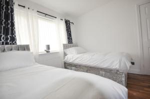 2 łóżka pojedyncze w sypialni z oknem w obiekcie Modern 2 Bed Apartment w Luton
