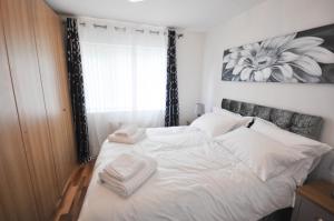 a bedroom with a white bed with towels on it at Modern 2 Bed Apartment in Luton +15 photos