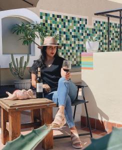 Eine Frau, die auf einem Tisch mit einem Glas Wein sitzt. in der Unterkunft Marisol Hotel Boutique in San José del Cabo