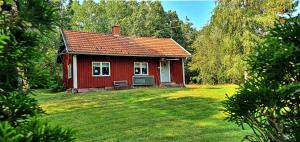 uma casa vermelha num quintal com um campo de relva em Lidsbergs torp i Ölme em Kristinehamn