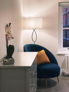 a blue chair sitting next to a desk with a lamp at James's Place on Oxford Street in London