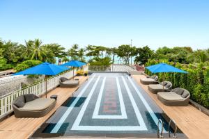 a swimming pool with chairs and blue umbrellas at Mera Mare Pattaya in Pattaya Central