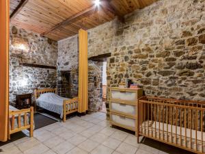 Habitación con pared de piedra, cama y cuna en Apartment near the river in Bize Minervois, en Bize-Minervois