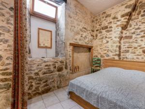 ein Schlafzimmer mit einem Bett in einem Zimmer mit Steinwänden in der Unterkunft Apartment near the river in Bize Minervois in Bize-Minervois