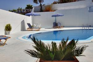 a swimming pool with chairs and umbrellas on a patio at Villa Pelekanos in Karterados