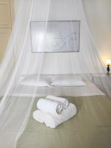 a bed with two white towels and a canopy at Family house by the seaside of Karavostasis in Karavostasi