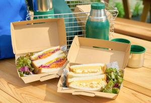 八王子市TAKAONE ACTIVITY＆STAY的两盒三明治和沙拉及饮料