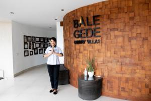 a woman is standing in front of a brick wall at Bale Gede Luxury Villas in Seminyak