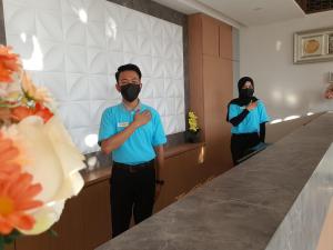 Ein Mann, der eine Maske vor einem Spiegel trägt. in der Unterkunft Muara Hotel Bukittinggi in Padangluar