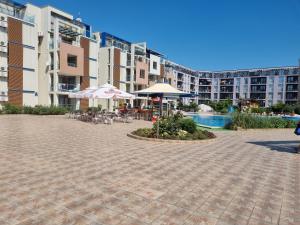 a patio with tables and umbrellas in front of buildings at Studio Apartment with balcony 300m from beach in Sunny Beach