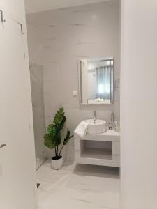 a white bathroom with a sink and a mirror at The Syntagma Luxury Suite in Athens