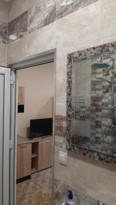 a bathroom with a shower and a television and a mirror at Арт in Sliven