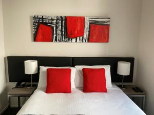 a bedroom with a bed with two red pillows at 315 Euro Motel and Serviced Apartments in Dunedin