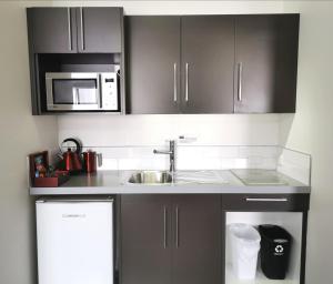 a kitchen with a sink and a microwave at 315 Euro Motel and Serviced Apartments in Dunedin