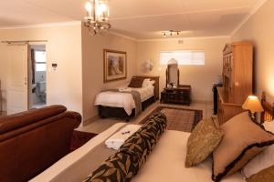 a bedroom with two beds and a couch in a room at Antiqua Guest House in George