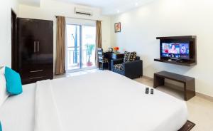 a hotel room with a bed and a television at Sanctum Suites Domlur Bangalore in Bangalore