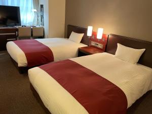 una camera d'albergo con 2 letti e una scrivania di Ai Hotel Keikyu Kamata-ekimae a Tokyo