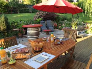 a wooden table with food and an umbrella on a patio at Les Chambres D'oriane in Chessy