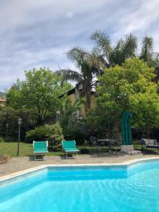 a swimming pool with two blue chairs and a table at Chorisia Relais in Roccapiemonte