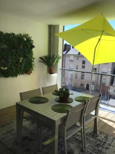 a dining room table with a yellow umbrella at Rodez Aveyron appart. T4 neuf 2 places parking in Rodez
