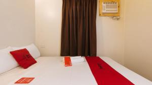 Un dormitorio con una cama con almohadas rojas y una ventana en RedDoorz near EDSA Camp Crame en Manila