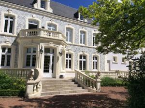 uma casa branca com uma escada em frente em Logis Hôtel & Restaurant - Le Château Des Tourelles em Le Wast