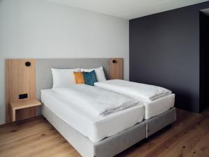 ein Schlafzimmer mit einem großen weißen Bett mit Kissen in der Unterkunft Hotel Neu-Schönstatt in Quarten