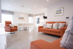 a living room with two orange couches and a kitchen at Sea Breeze in Portstewart