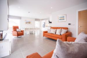 a living room with an orange couch and chairs at Sea Breeze in Portstewart